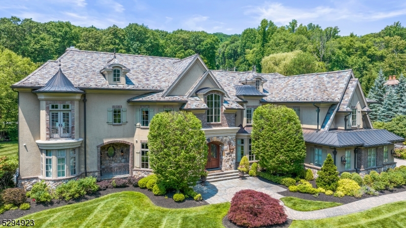 Elegance, luxury & perfection define this estate in the desirable neighborhood of "The Pond" in Montville Twp. A grand entrance welcomes you showcasing custom woodwork & architectural brilliance. An open floor plan seamlessly connects each space, beginning w/ a custom bar room featuring coffered ceilings & built-ins, with access to the outdoors. A formal dining room adjoining a butler's pantry is perfect for entertaining. The great room boasts cathedral ceilings, wood-burning fireplace & stunning arch floor-to-ceiling windows that open to a beautiful patio. The highlight of this home is the custom kitchen, equipped w/ 2 center islands, quartz countertops, state-of-the-art appliances, pizza oven, separate eating area w/ gas fireplace & an abundance of windows. The 1st fl includes a full theater room, game room, bedroom w/ full bath & mudroom with custom built-ins. On the 2nd level, the primary bedroom suite offers a gas fireplace, huge walk-in closet w/ a center island, & lavish bath w/ dual vanities & marble/onyx steam shower. French door opens to a private balcony overlooking serene landscaping. 3 additional en-suite bedrooms w/ walk-in closets, a loft, laundry room, complete the 2nd level. 3rd level offers a private office, or reading area. This masterpiece features a slate roof, copper gutters & paver driveway. The outdoor area is perfect for entertaining, w/ a built-in kitchen that includes a refrigerator, gas grill, sink, & storage, all surrounded by custom stonework.