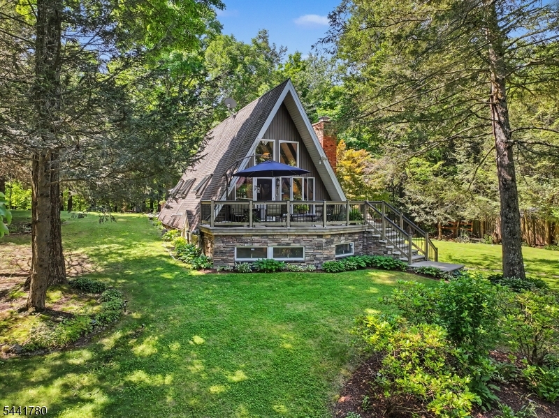 Tucked among the trees, where privacy is endless and nature takes center stage, lies an enchanting A-Frame unlike anything you've seen before. From the moment you step through the door, you're captivated by timeless charm, where every room tells a story. The main living area is warmed by a pellet stove, creating the perfect gathering place, while the character-filled kitchen showcases artistic touches rarely found in today's homes. A spacious dining room framed by picture windows captures peaceful woodland views, seamlessly bringing the beauty of nature indoors. Above, a loft-style bedroom offers a cozy retreat. The lower level, accessible from the side of the home a living room with a woodburning stove a wet bar, full bath, laundry area, and abundant storage. Step outside to your own private woodland sanctuary. A beautifully designed paver patio, charming pergola, and twinkling lights create a magical setting for entertaining or unwinding beneath the stars. Backing directly to state land, the property offers exceptional privacy and a breathtaking natural backdrop in every season. A rare bonus awaits across the street with an additional lot featuring a massive two-car garage complete with electric and water. Ample paved parking provides room for an RV, boat, recreational vehicles, or future projects. More than just a home, it's a retreat where every day feels worlds away from the ordinary.
