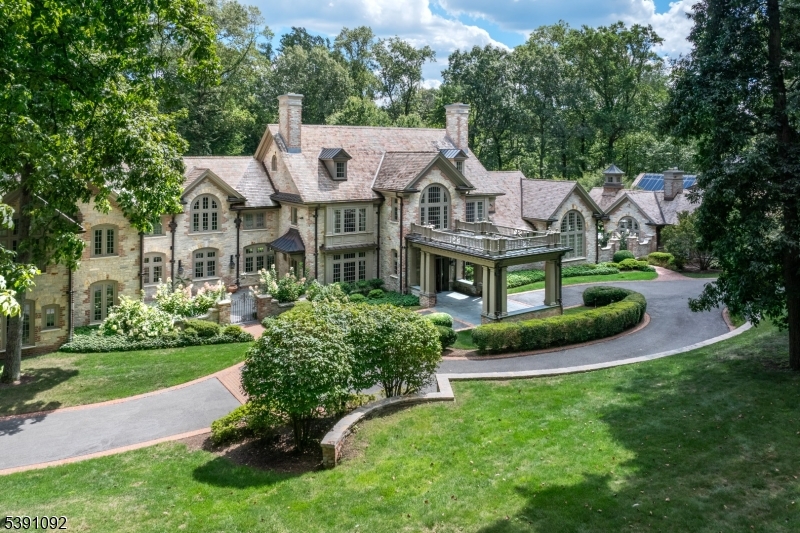 An architectural masterpiece on the Bernardsville Mountain is set on 5+ manicured acres. Acclaimed architect Peter Dorne designed this exceptional dwelling in 2012; it features a separate pool house with a state-of-the-art squash court and adjacent sun-filled conservatory. The gracious interior offers six bedroom suites, one of them a well-appointed two-bedroom apartment, seven full baths and two powder rooms. Bespoke design elements include hickory wood flooring, ornate fireplaces, Charles Edwards lighting fixtures, modern Waterworks baths, extensive built-ins, exquisite millwork, French doors and an elevator. This brick and stone manor is surrounded by exceptional masonry work, bluestone terraces, porte cochere front entrance, mature trees, open lawns and colorful gardens, making it a quintessential country home. Privately sited at the end of a cul de sac where it shares a rear border with the Somerset Hills Country Club, it's just minutes from Bernardsville's lively village. Audio recording on premises.