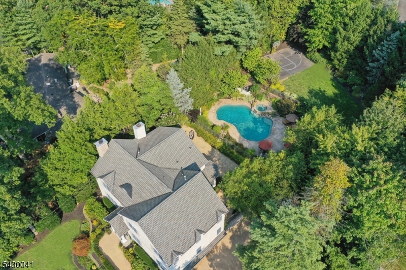 Exceptional newer construction located in the highly desirable Deerfield neighborhood of Short Hills. This stunning 6-bedroom, 5.5-bath home offers luxurious living with hardwood floors and recessed lighting throughout. Sun-filled living room with wood-burning fireplace flows into the recently renovated eat-in kitchen featuring custom white and gray cabinetry, quartz countertops, designer backsplash, walk-in pantry, and ample storage. Oversized family room with custom built-ins, gas fireplace, and French doors leading to the patio and outdoor firepit. First floor includes a private in-law suite with full bath plus a flexible office/gym/guest room. Luxurious primary suite with tray-vaulted ceiling, two walk-in closets, and spa-like bath with dual vanities, oversized shower, and soaking tub. Separate office with custom built-ins overlooks the private backyard and inground pool. Junior suite with full bath and walk-in closet plus two additional bedrooms connected by a Jack-and-Jill bath complete the second level. Finished basement offers rec room, playroom, full bath, mudroom, and access to attached 3-car garage. Enjoy your private outdoor oasis with multi-level patio, inground pool, level backyard, and basketball court. A rare opportunity offering space, luxury, and exceptional amenities in one of Short Hills' most sought-after neighborhoods.