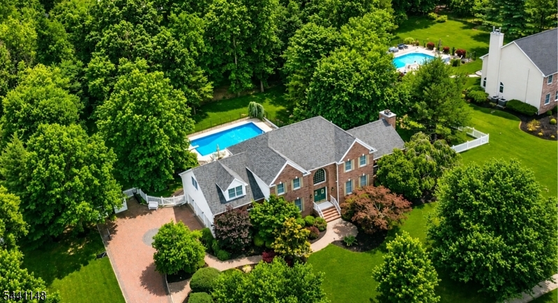 Northeast facing brick front Grand Colonial on a premium wooded lot in desirable Belle Mead. Dramatic two story foyer with curved oak staircase and hardwood floors throughout. First floor bedroom/study with full bath. Gourmet kitchen with granite countertops, bay window breakfast area, and premium appliances including a 6 burner Thermador gas range, Thermador wall oven/microwave, Thermador hood, Bosch dishwasher, and Sub Zero refrigerator. Spacious family room with cathedral ceiling and wood burning fireplace. Luxurious primary suite with vaulted ceiling, sitting room, walk in closet, and bath with skylight and Jacuzzi. Large secondary bedroom with vaulted ceiling. Finished attic, semi finished basement with cedar closet, central vacuum, French drain, ample storage, alarm system with wired video surveillance, whole house generator, and fresh air ventilation system. Four zone hot water baseboard heat and two zone A/C with UV C, ionizer, and Lennox MERV16 whole home air purification. Resort style backyard featuring a huge heated in ground pool, fenced yard, professional landscaping, landscape lighting, 8 zone sprinkler system, oversized shed, paver driveway and walkway, and 3 car garage. Public water and sewer. Montgomery Township Blue Ribbon Schools. Updates: Water heater (2020); generator, roof, gutters, A/C, and paver driveway/walkway (2021); Thermador appliances, Sub Zero refrigerator, washer, dryer, and pool liner (2024).