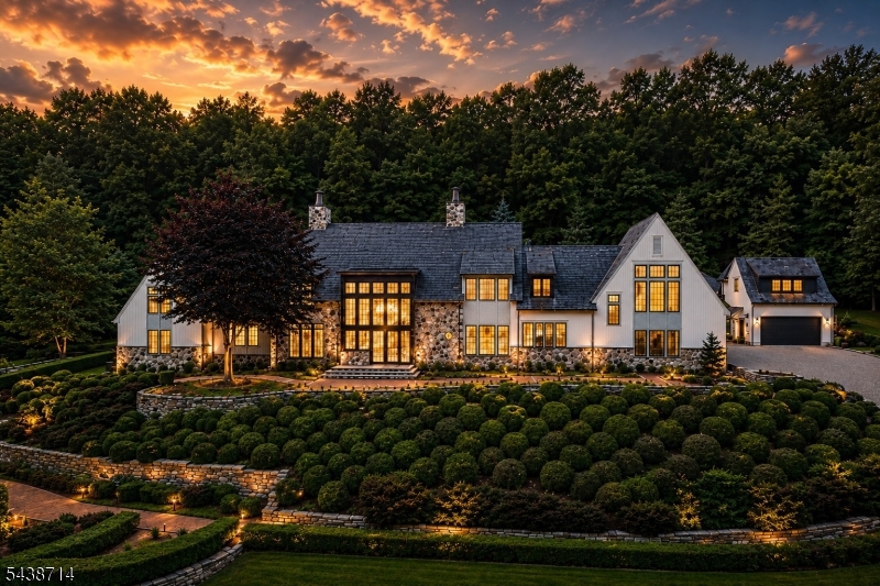 Set on 12.45 private acres within the prestigious Bernardsville Mountain enclave, surrounded by mature woodland and beautifully maintained grounds. Timeless European-inspired architecture, handcrafted stonework, soaring walls of glass, custom millwork, designer finishes, and European White Oak flooring define the residence throughout. Designed for everyday living and grand-scale entertaining, the home features 5 bedrooms, 6 full bathrooms, and 3 half bathrooms. The gourmet kitchen showcases a dramatic bookmatched Calacatta Oro stone feature wall, custom cabinetry, expansive center island, and adjoining butler's pantry. Multiple gathering spaces include a grand living room, formal dining room, private office, library-inspired retreat, and spacious family room. The luxurious primary suite offers a private lounge with wet bar, boutique-inspired dressing rooms, and a spa-like bath with a sculptural soaking tub, dual shower suites, and exquisite marble finishes. The lower level features a custom-crafted wine cellar, recreation spaces, and additional entertaining areas. A detached carriage house provides a private guest suite with full bath, wet bar and soaring ceiling. The attached garage accommodates up to 7 vehicles with lift capability. A rare offering combining exceptional craftsmanship, privacy, and luxury living, just moments from Bernardsville's renowned country clubs, equestrian amenities, fine dining, highly rated schools, and convenient access to New York City.