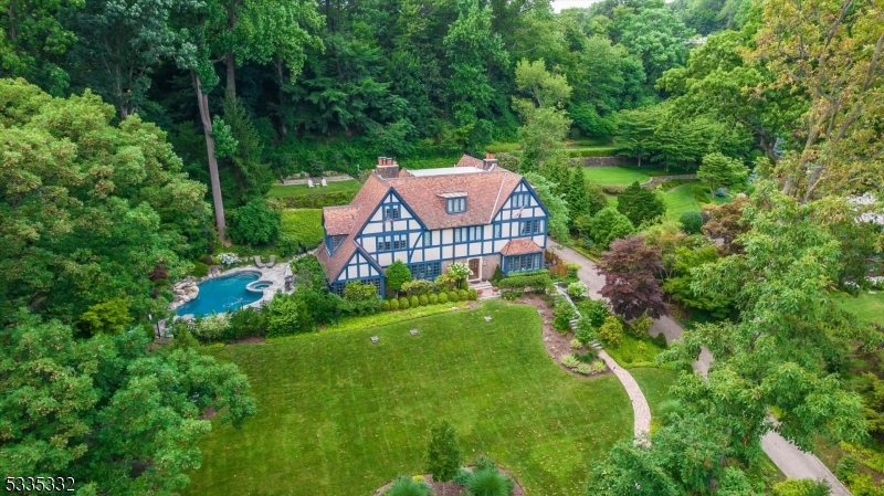 Perched on a sweet spot of Highland Avenue sits this elegant Tudor style home that defines love where you live. Unmatched skyline views can be enjoyed in all four seasons. Lush landscaping sweeps you up the property leading to the stately front entry and welcomes you home, where exquisite architectural details are found at every turn. The first floor features a spacious living room w/fireplace, leading to the sunroom with views of the in-ground Gunite heated pool with waterfall. The custom lighting and landscaping will make you feel like you're in Shangri-La in Montclair. Library, formal dining room, private powder room, cooks kitchen and breakfast room w/gas fireplace complete the first floor. The kitchen has high end appliances, including a double Wolf stove and SubZero fridge. Most bedrooms are ensuite and many have heated floors. The luxurious primary suite features a spacious bedroom with sitting room and dressing room with walk-in closet. From the kitchen you can access a second staircase leading up to two bedrooms and a full bath. Ideal floorplan for a guest suite. Endless possibilities in this flexible floorplan. Lower level gym and steam room - ditch your gym membership! This home is made for entertaining. A showpiece that also feels like home. Additional amenities include a generator, 3 car garage with pollinator garden above garage, newer AC units, terracotta roof and more. Come and experience true pride of ownership where no detail has gone overlooked.