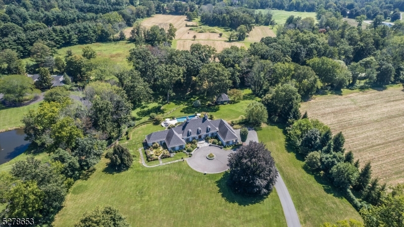 Majestically situated on the prestigious Van Beuren Road in Harding, this gorgeous four-bedroom, five full and one-half bath custom home seamlessly blends timeless elegance with modern luxury. Originally crafted by Timson in 1963, this exceptional residence underwent a thoughtful transformation in 2014 with elevated attention to detail and design. The first floor boasts an abundance of natural light and a flexible floor plan designed for everyday living and entertaining. Adjacent to the impressive formal living room is the gourmet kitchen, breakfast room, butlers pantry and dining room. Not to be missed is the stunning den made cozy with a gas fireplace. The main floor is home to the luxurious primary suite, boasting a spa-like bath with a soaking tub and stall shower, along with two walk-in closets. An additional en-suite bedroom on the first floor provides comfort and convenience for guests. Upstairs, two more en-suite bedrooms await, each with a walk-in closet. The allure of this exceptional residence extends beyond its interiors to the meticulously landscaped grounds. Trex decking, multi-level blue stone patios, one with a fireplace, a heated gunite infinity pool with a sun shelf and waterfall, and a separate hot tub create an outdoor oasis for relaxation and recreation. With its unparalleled blend of timeless elegance, modern amenities, and fine craftsmanship, this Timson original epitomizes a comfortably elegant lifestyle and resort-like living.