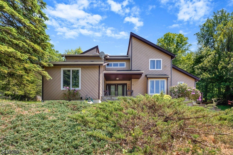 Nestled on a beautifully landscaped wooded property, this striking CUSTOM 5 BEDROOMS and 3 FULL BATHS contemporary home offers a rare blend of privacy, architectural character, and peaceful retreat style living. Surrounded by mature trees and natural beauty, the home is designed to bring the outdoors in with expansive ANDERSON 400 windows, soaring ceilings, warm natural textures, and inviting living spaces filled with light. Thoughtfully designed for both everyday comfort and entertaining, the home features spacious rooms, hardwood flooring, dramatic architectural lines, multiple outdoor living areas, and a stunning stone fireplace that anchors the heart of the home. The expansive wraparound deck overlooks serene wooded surroundings, creating the perfect setting for morning coffee, quiet evenings, or gatherings. FIRST FLOOR BEDROOM with a FULL RENOVATED BATH. 1ST Floor LAUNDRY. Upstairs you'll find an indulgent primary suite with a walk-in closet & RENOVATED large bath. An additional 3 bedrooms & 1 full RENOVATED bath complete this floor. Tons of storage in a 2 car garage or full unfinished basement. Great location, just minutes from Union Hills Shopping Center, Denville's bustling DWTN, Morristown Green, NYC-Direct transport & easy access to major highways. Highly rated schools! Roof with 50 YEARS shingles! TANKLESS water heater! LEASED SOLAR ROOF! 7 years left. LED lights that can change colors! Kitchen with new refrigerator, dishwasher, range! ALL BATHROOMS RENOVATED!