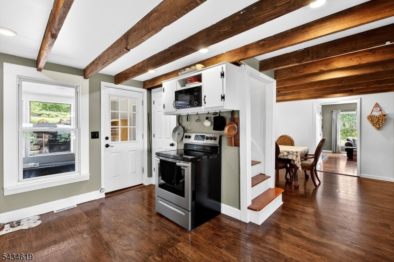 Perched in a picturesque setting with sweeping scenic views, this beautifully updated home blends timeless character with modern comfort. From the moment you arrive, the inviting covered porch, charming exterior, and peaceful surroundings create the perfect retreat atmosphere.Inside, the home showcases warm hardwood floors, exposed wood beams, and abundant natural light throughout. The spacious kitchen offers a perfect mix of rustic charm and functionality with rich wood accents, extensive cabinetry, stainless steel appliances, and generous prep space ideal for everyday living or entertaining guests. The open-concept living area features a striking wood-burning stove, oversized windows, and French doors that frame the stunning outdoor scenery.Enjoy seamless indoor-outdoor living with multiple spaces to relax, unwind, and take in the tranquil surroundings. Thoughtfully maintained and full of character, this property offers a rare combination of comfort, privacy, and charm while still being convenient to nearby amenities.Whether you're looking for a full-time residence, weekend getaway, or entertainer's dream, this one-of-a-kind home delivers warmth, style, and unforgettable views.