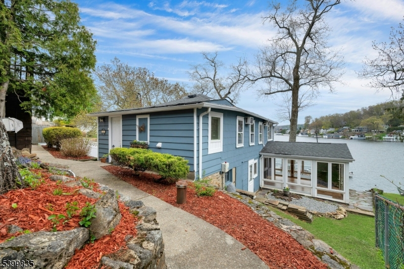 Enjoy year-round lake life in this charming lakefront home on Lake Hopatcong, New Jersey's largest man-made lake where motorboats are allowed. Offering 3 bedrooms, 1.5 baths, and parking for up to six cars.This property blends convenience and unbeatable recreation including - boating, fishing, ice skating, and much more. Located just minutes from major roads, restaurants, hiking, skiing and NJ Transit trains. The ground level features the kitchen, a half bath, dining/ family room, a sun room, warmed by a pellet stove; complemented by electric heat. Upstairs are three bedrooms, one with stunning lake views, one with a vaulted ceiling, ceiling fans, and wall air conditioners. An updated full bathroom with a modern walk-in shower.and a stackable washer/dryer complete the first floor. Outdoor living shines with a spacious deck, stone pavers, fully fenced yard and a firepit area ideal for entertaining. Additional highlights include a state of -the- art updated 3 bedroom septic system and optional membership to Elba Point Beach Club, which offers a private beach, club house,  boat/watercraft slip rentals, picnic area and more. Recent updates include: New flooring, some windows and fencing were replaced, freshly painted, newer water heater & well pump and the deck was refinished. Driveway railings,stairs & landing were refinished. Don't miss your chance to own this lakefront property with year-round fun and breathtaking views. It's more than a home, it's a lifestyle!.Chimney As Is.