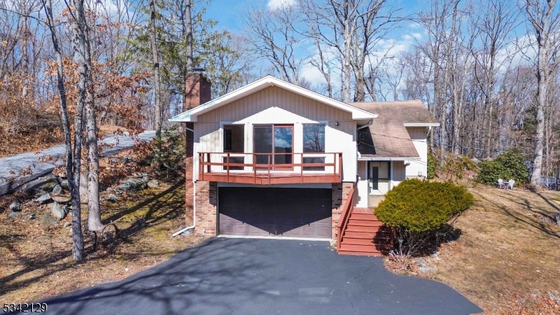 Tons of Character in a Great Location! Lovely bi-level home  set on a 0.55-acre corner lot in Sparta, boasting 3 bedrooms, 2 full baths and attached 2-car garage. The main level opens with a spacious and sun-filled living room with hardwood floors, vaulted and beamed ceiling, cozy wood-burning fireplace, and a balcony that's perfect for sipping coffee or cocktails. Past an eat-in kitchen with classic wood cabinetry you'll find 2 bedrooms with large closets serviced by a full hall bath with stone-topped storage vanity and tub/shower combo. At the end of the hall is a generous primary bedroom suite with adjoining full bath with shower, as well as rear access to an oversized deck overlooking the bucolic wooded surroundings. There's additional living space in the lower level, offering a large family/rec room for everyday relaxing and entertaining, a private office space, laundry, garage access and a foundation/rock room that can be used for wine cellar or just something unique for this home. Downtown Sparta is just a mile away with all the essentials, plus easy access to Rt. 15 for effortless commutes. You'll also enjoy deeded membership to Sparta Hills Beach Club with swimming, fishing, and boating on nearby Lake Saginaw for endless recreation. Don't pass up this gem