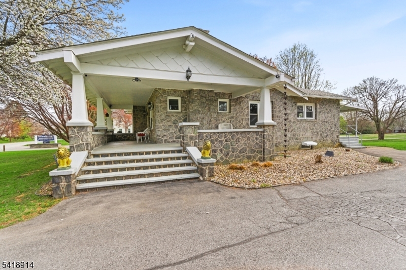 Welcome Home to this beautiful stone custom home. Sunlight pours into this stunning stone home, where timeless charm meets thoughtful design, all set on a beautiful, expansive lot with picturesque views in Lopatcong Township. From the inviting wrap-around porch to the character-rich stone exterior, every detail welcomes you in. Inside, rich wood flooring and custom oak moldings create a warm, elegant feel throughout. Everything is located on one floor. The heart of the home is a beautifully designed kitchen featuring granite countertops, stainless steel appliances, a wall oven, a gas cooktop, and stylish two-toned cabinetry with abundant storage. It flows seamlessly into a formal dining room, then into a spacious, cozy family room highlighted by a striking stone fireplace and a sun-filled picture window. Perfect for both everyday living and entertaining, the kitchen opens to a covered porch and deck, ideal for relaxing and taking in the serene surroundings. Large Attic with pull-down stairs. An unfinished basement offers a blank canvas, ready for your personal touch. This home has three bedrooms and a two-car detached garage. This home offers comfort, character, and a setting you'll truly love. Shopping, restaurants, and all of the modern conveniences in a rural country setting. Close proximity to local parks. The fireplace and chimney are being sold as-is with no known defects.