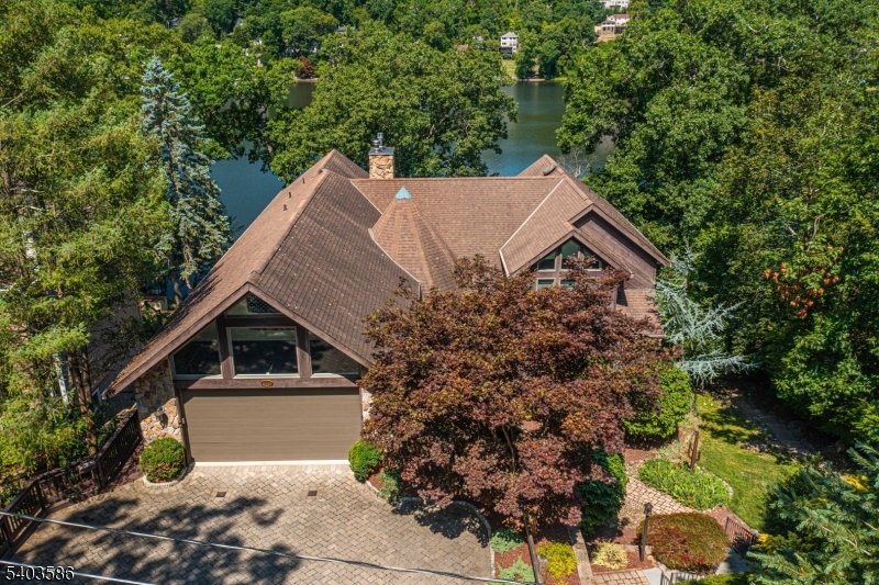 Stunning Cedar Lake Waterfront Retreat! This exceptional custom lakefront home offers over 4,000 sq ft of beautifully designed living space with breathtaking views of the Lake from nearly every angle. The dramatic interior features cathedral ceilings, walls of windows, & a striking floor-to-ceiling stone gas fireplace that anchors the main living area in warmth & elegance. A true highlight is the 1-floor primary suite, complete with a balcony overlooking the lake, creating a peaceful retreat with incredible views. The spacious layout is ideal for both everyday living & entertaining, seamlessly blending indoor comfort with the natural beauty of the waterfront setting. Upstairs, an additional 2 bdrms & den. The home includes 4.5 baths, an oversized 2 car garage, paver driveway & a full, walk-out bsmt, offering endless potential for future living space or storage. Outdoor living shines with a multilevel trex/cedar deck and private dock, perfect for enjoying sunsets, lake activities, & the serene surroundings. Motorized awnings shade the Western front. A rare opportunity to own a truly custom waterfront home with remarkable space, architectural character, & unforgettable lake views in desirable Denville. Rectangle shaped lot in a private section of the lake community. Public sewer hookup available for future use. Generator hookup. Close proximity to DWTN Denville & Boonton Main with all its shopping, dining & events with easy access to major highways & NYC direct transit.