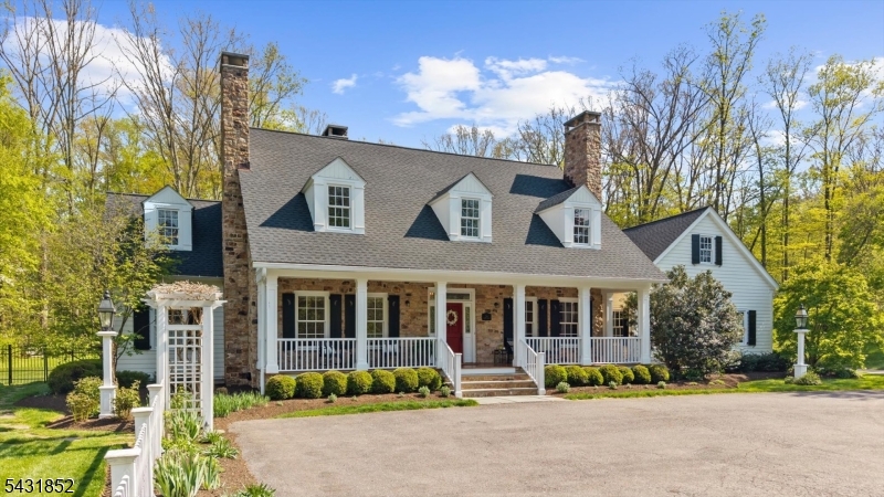 Tucked into a picturesque setting, this custom home was thoughtfully designed to capture timeless architectural detail and effortless flow throughout its beautifully scaled living spaces. Inspired by the warmth and character of a Louisiana Low Country Colonial, the residence blends classic craftsmanship with modern comfort in a way that feels both refined and welcoming. French doors open from the principal rooms and first-floor primary suite to a deep, full-length flagstone veranda framed by stone walls and lush gardens that surround the property with color and privacy. At the heart of the home, the country kitchen features an iconic AGA range cooker serving as a timeless, heavy-duty focal point, blending old-world charm with everyday function. The kitchen and breakfast area connect seamlessly to the family room anchored by a striking stone fireplace, while additional fireplaces create inviting focal points in both the library and dining room. A rear hall offers two additional bedrooms, full bath, powder room, pantry, and laundry area, creating a flexible and functional layout. The second-floor staircase opens to a generous recreation room with office, fourth bedroom, and full bath, ideal for guests or extended living space. Outdoors, the highly upgraded heated saltwater pool and entertaining areas create a private retreat that perfectly complements the home's peaceful surroundings. Just minutes to Oldwick and 78. Roof (2025), First Level HVAC (2025), Generator (2020).
