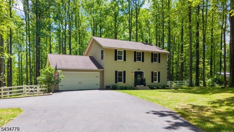 The first thing you notice is how quiet it is. 1.72 acres backed by woods gives this property a removed, settled feeling that's hard to come by. Inside, the layout is open and easy to move through, with a living room that gets great natural light and a family room centered around a wood burning fireplace, exactly where you'll want to be once the temperature drops. The kitchen has light cabinetry, room to actually cook, and a breakfast bar that keeps things casual, while the adjoining dining room handles the bigger sit-down occasions just fine. Out back, a porch and deck give you real outdoor living space, morning coffee, summer dinners, or just watching the tree line do its thing. Upstairs, four good-sized bedrooms give everyone room to breathe. The primary has its own full bath, a walk-in closet, and a dressing area. Two and a half baths total mean the morning rush stays manageable, and the two-car garage plus full basement means you'll never run short on storage or wonder what to do with the extra square footage. The location sits out far enough to feel like the country but close enough that errands don't become an event. And from fall through winter, when the leaves come down, you pick up views of Furnace Lake nearby, a quiet bonus that makes the colder months a little easier to appreciate.