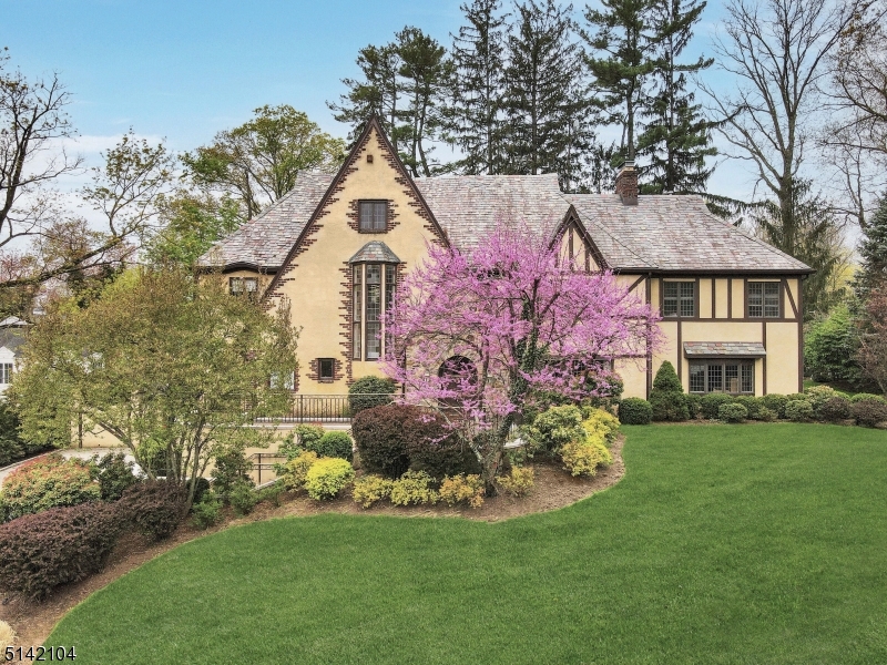 The beauty and enchantment of this luxurious Short Hills Tudor is indescribable! The architectural gem with slate roof, stunning stonework, striking peaks and paver drive has curb appeal galore and is truly a forever home. Set on .38 acres of lush landscaped grounds, this gracious residence enjoys a prime location near train, shopping, highways, top schools and more. Impeccably designed interiors present grand living-entertaining areas, 7 bedrooms and 4.2 baths. Tranquil outdoor spaces include a blissful bluestone patio with nearby wood-burning firepit for alfresco dining/entertaining and magnificent broad flat partially fenced yard for recreation. Unlike many Tudors, ample light streams in through generous oversized windows. The sophisticated, inviting main level greets you with an elegant reception hall and presents an expansive living room with wood-burning fireplace, wood beams and massive windows. Adjoining is a wainscoted dining room for hosting guests in style with French doors to the outdoor oasis. Plus a sun-filled family room with built-ins; new white chef's kitchen; divine primary suite with custom walk-in closet, 2-person office and spa bath; third floor with 3 bedrooms -- perfect for guests, offices or multipurpose; finished lower level with recreation and exercise rooms, laundry and 3-car garage. This magical house on a quiet street also has a standby generator. As alluring is the prime address near it all and a 5-minute stroll to top-rated Glenwood Elementary.