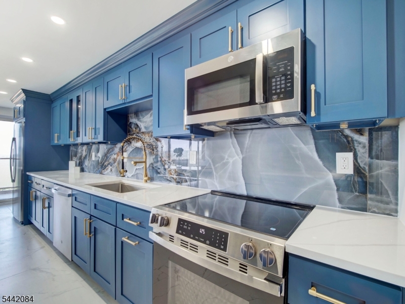 Welcome to luxury co-op living in this beautifully reimagined, high-end residence where sleek modern aesthetics meet sophisticated comfort. The heart of the COOP is a showstopping designer kitchen blending custom deep-blue cabinetry with gold hardware, a dramatic high-gloss marble backsplash, and a massive peninsula island with a flawless waterfall quartz countertop. This exceptional open flow transitions seamlessly into the expansive, sun-drenched living room where oversized panoramic windows frame sweeping town and treetop views, and a sliding door leads to your own private terrace retreat finished with privacy-glass railings. The continuous marble-look flooring carries you into two peaceful, airy bedrooms that both offer elevated vistas and abundant natural light, all serviced by an ultra-modern, spa-inspired bathrooms including floor-to-ceiling marble tile and appointed with luxurious gold fixtures, a glass-enclosed tub, and a contemporary backlit LED smart mirror. Coop features a 24 concierge, incl utils (electric, heat, hw), underground parking ($60/mo), complimentary jitney to the NYC train and grocery stores, a backyard mature "secret garden", first floor gym and bright, bsmt laundry. Blocks from access to GSP and Route 280. Coop board approval required and 20% down payment is a must. 418 ownership shares. Monthly maint $2014. HOA includes taxes, maintenance and all utilities (heat/AC, hot water, electric). See details on entrance requirements and move-in fees.