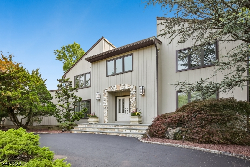 A designer-curated Custom Contemporary Colonial style home offering 6 bedrooms and 3.1 baths around 3500 Sq Ft w/o basement, defined by impeccable craftsmanship and timeless elegance. Rich custom oak hardwood flooring and extensive millwork including elegant crown moldings upgraded baseboards and trim, create a sophisticated, cohesive aesthetic throughout. Interior doors are enhanced with premium hardware. The one of a kind eat-in kitchen is a true statement space, showcasing abundant handcrafted shaker-style cabinetry crafted from lacewood and walnut, a striking slate backsplash with decorative metal inlays, granite countertops, high-end stainless steel appliances, and a substantial butcher block island with seating. A thoughtfully designed first floor includes a bedroom and a laundry room for added convenience. The primary suite serves as a luxurious retreat with three closets, including a walk-in, and a spa-inspired bath with a custom soaking tub and oversized shower. Entertain with ease in the screened-in porch with skylight and ambient lighting, or extend gatherings outdoors to the expansive yard and deck with integrated grill and dining area. Additional highlights include Pella windows, built-in garage storage, house generator, and professionally landscaped grounds with irrigation and lighting. The exterior is finished with cedar siding and stone accents, complemented by aluminum soffits and trim. A circular driveway enhances curb appeal and provides ample parking.