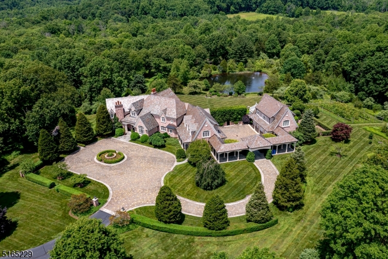 McMurtry Farm is a magnificent 217-acre estate property in Bedminster's famed horse country. This unique offering is held in 6 parcels and includes the custom 15,000+-sq-ft manor house spanning 3-levels, a separate one-bedroom apartment, beautiful climate-controlled greenhouse, stone patios, brick walls, pond with waterfall, tennis court, and extensive gardens. Brick, limestone and a slate roof envelop the residence sited majestically at the end of an extraordinary mile-long picturesque drive through acres of rolling fields and woodlands. Custom architectural details abound from the raised panel wainscot, crown molding and intricate millwork to the 2-story cherry-paneled library and 1st-floor media room. In the foyer, a curved floating staircase to the upper and lower levels is dramatically eye-catching. Beautifully scaled, finely detailed rooms feature hardwood and stone floors, high ceilings, French doors and four fireplaces. All bedrooms are en-suite with walk-in closets. The lower level offers a wine cellar, gym, billiards room, playroom, kitchenette, and full bath. With mature trees, gardens, thoughtfully designed landscape and hardscape, the residence is poised on a rise overlooking sweeping lawns and a magnificent well-fed pond and waterfall. The expansive rear bluestone patio allows for views of the lush scenery. For the car enthusiast, there are 7+ bays and a heated motor courtyard. A separate private one-bedroom apartment rounds out this incredible offering.