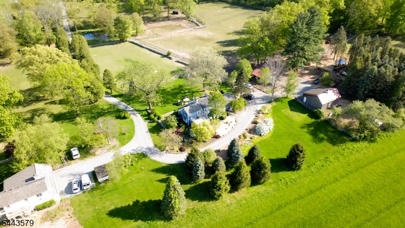 Tucked away at the end of a tree-lined driveway on coveted Hollow Brook Road, this exceptional 16+ acre country farm estate offers privacy, serene pastoral views, and direct access to the Tewksbury Trail System. Surrounded by preserved farmland, the thoughtfully updated 1820s farmhouse seamlessly blends historic character with modern comfort, showcasing hand-hewn beam ceilings, wide-plank pumpkin pine floors, updated kitchen, and newer windows, a whole-house generator, and a digital well system with whole-house and barn water filtration. Relax on the inviting front porch overlooking fenced pastures and pond, or unwind in the unique bee therapy shed, a peaceful sanctuary. Designed for horse enthusiasts and animal lovers, the farm-assessed property features 5 fenced pastures, 2 large pole barns, 4 horse stalls, run-in sheds, and frost-free hydrants/drinking posts in every pasture. A detached three-car garage is complemented by a legal two-bedroom apartment - one with its own entry - and a private en-suite full bath, plus a shared kitchen and great room, ideal for guests, a caretaker, or rental income. The lower level offers a workshop, laundry, storage, and a fenced and covered outdoor area perfect for entertaining, as a play area or for pets. Enjoy spectacular sunsets,  farm pursuits, gardening, entertaining and a tranquil country lifestyle in one of Hunterdon County's most sought-after locations, just 1 hour from NYC, and in a Top-rated Blue Ribbon school district.