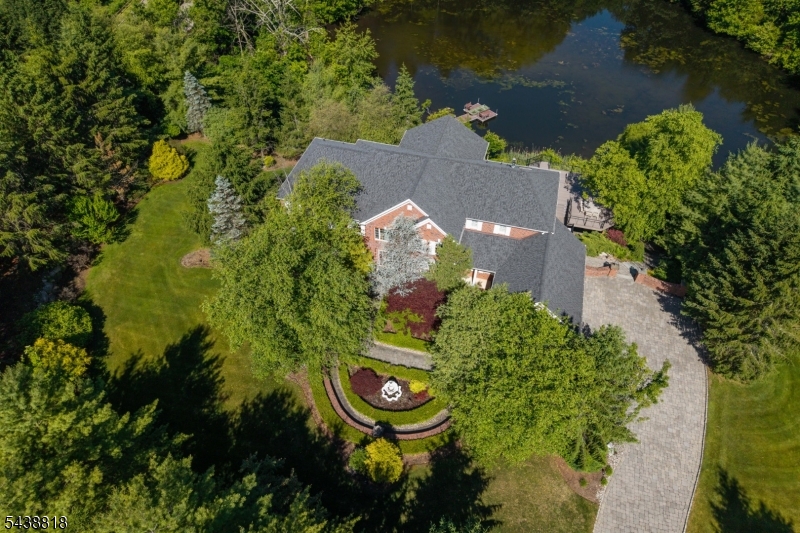 Set on nearly four private acres, this exceptional custom residence offers a rare blend of luxury, privacy, and natural beauty.Overlooking a private pond complete with a dock and tranquil water views, this remarkable property delivers an extraordinary lifestyle in a picturesque Sparta setting.A grand two story foyer welcomes you into beautifully appointed interiors where sunlight pours through expansive windows, illuminating hardwood floors, custom millwork, and inviting living spaces anchored by four gas fireplaces.At the heart of the home, the chef's kitchen blends elegance and functionality, featuring rich Yorktowne Cherry cabinetry, Cambria Rose Bay quartz countertops, a generous center island,Sub-Zero refrigerator, double ovens, and a walk-in pantry.Designed for both entertaining and everyday living, the home offers spacious bedrooms, renovated bathrooms, and a private study.The finished lower level elevates the experience of home with a custom bar, billiards area, expansive recreation space, and your own private cinema. Step outside to a peaceful outdoor retreat.Enjoy views of the water from the Trex deck, launch a kayak from the dock, cast a line into the private pond, or simply take in the beauty of the surrounding landscape.Enhanced by extensive updates, smart home technology, and a three car garage, this exceptional residence offers a seamless blend of sophistication, comfort, and recreation.More than a home, it is a destination where every day feels like a retreat.