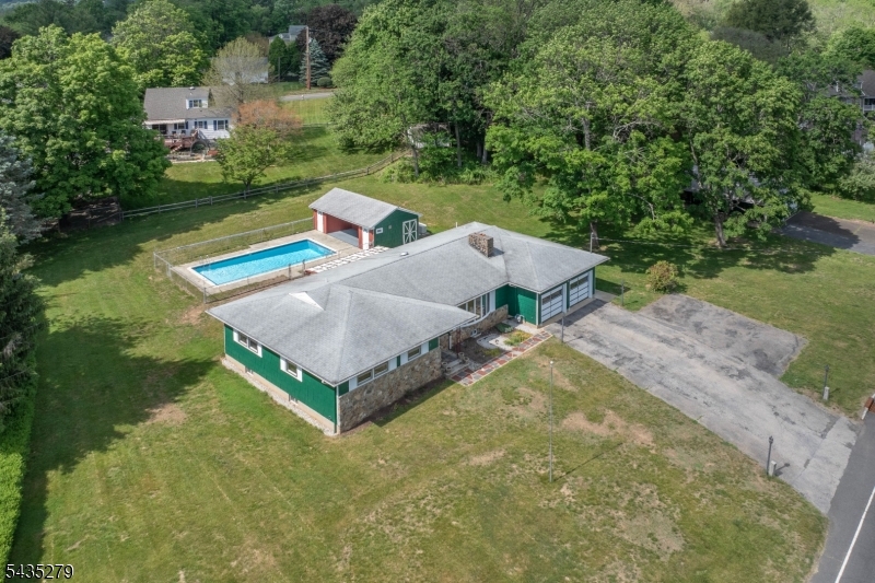 Spacious and full of potential, this 4-bedroom ranch offers the ease of one-story living in the heart of bucolic Peapack-Gladstone. Featuring 3 full baths and 2 half baths, the home includes a generously sized eat-in kitchen and an expansive family room with a cozy gas fireplace perfect for everyday living and entertaining. There is a large mud laundry room with an expansive walk-in closet. A huge partially finished basement with a classic old-time bar provides additional space for gatherings and recreation. Step outside to enjoy the inground pool, complete with a pool house and a full bath, creating a true backyard retreat. The property also includes a separate outbuilding ideal for a wood shop, studio, or hobby space. While the home offers a wonderful layout and setting, it presents an excellent opportunity for updates and personalization. All this just blocks from the NYC train, fine dining, parkland, trout stream, Somerset County library, and local amenities, including brand new tennis and pickleball courts, and is located within a highly regarded school district.