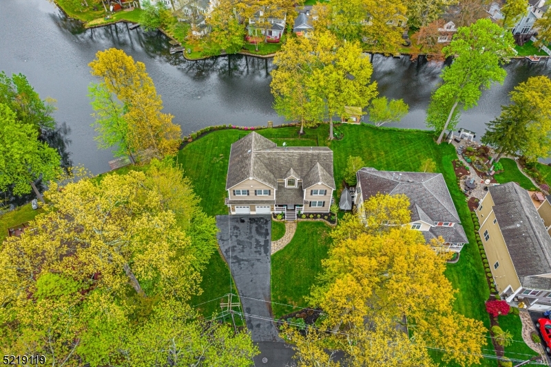 Stunning LAKEFRONT on double lot with sweeping views of an idyllic setting. Striking open floor plan & custom details create fabulous entertaining 1st floor living. Winning features include the stone/gas fireplace, built-in bookshelves, hardwood flooring, recessed lighting, high ceilings. Open Dining to Gourmet Kitchen w/high end appliances, granite, center island w/breakfast bar, pantry & center window overlooking the lake. French Doors lead to 5th bedroom, office or den & full bathroom + another lovely room w/lake views & dramatic 2-story foyer complete the 1st floor layout. The open staircase leads to an impressive primary suite; the wall of windows overlooking the lake, 2 walk-in closets, tray ceiling & huge bathroom w/super-sized shower, soaking tub, 2 sinks-give this peaceful resting space real bragging rights. The other 3 bedrooms, bath & laundry room along with great closet space are impressive. The finished attic space/penthouse is a bonus for whatever more you need in a home; 6th bedroom, media or playroom. The setting for this gorgeous home is perfectly placed on a manicured, fenced, level double lot. From the inviting, cozy front porch to the scenic back deck, just move in & start communing w/nature. Backyard boating, fishing, ice-skating in the winter. Indian Lake offers 3 beaches w/lifeguards, an active community & clubhouse-the time is now to start living your best life. Walking distance to downtown Denville restaurants. NYC Bus &Train. Top rated schools.