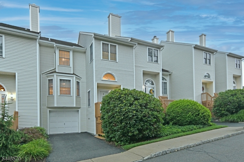 Welcome to Skyline Village! This meticulously maintained townhouse features two bedrooms and two and a half bathrooms, complemented by a finished basement and an attached one-car garage. Upon entering, you are welcomed by an elegant tiled foyer, which includes a spacious coat closet. The first floor showcases an updated half bath and a large eat-in kitchen with a breakfast area, equipped with granite countertops and stainless steel appliances. The dining room, adorned with hardwood flooring, offers sliding doors that lead to a private deck, surrounded by tranquil scenery. The living room impresses with soaring cathedral ceilings, a wall of windows, skylights, and a cozy gas fireplace. On the second level, you will find the primary bedroom, featuring a walk-in closet, an additional closet  and an updated full bath. The second bedroom is bright and inviting, with access to another updated full bath. The full, finished basement includes a laundry area, ample storage space, and a designated office/gym area, along with access to the oversized one-car garage. The community amenities include a heated pool and clubhouse, all within minutes of downtown and conveniently located near major highways and the NJ Transit Bus and Train Center.