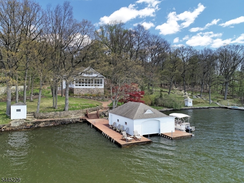 Escape to one of Lake Hopatcong's most extraordinary island retreats, where timeless craftsmanship, classic lake charm, & unforgettable waterfront living come together. This meticulously maintained, fully furnished Halsey Island residence showcases exceptional woodwork, stained-glass accents, oversized rooms & an expansive open floor plan designed for entertaining & gathering. 4 BR's, 7 baths & a massive loft, the home accommodates up to 18 guests, making it the perfect destination for friends, weekend getaways. The spacious living room, dining area & kitchen flow seamlessly together, while a spectacular glass-enclosed porch overlooks the lake & a shuffleboard area. The expansive 2nd level offers flexible space for gaming, lounging, addt'l sleeping quarters, or for simply relaxing after a day on the water. Step outside to two private boat slips, a charming boathouse, gazebo, playhouse, stone lakeside patio & endless opportunities to boat, swim, water ski, fish, kayak or simply unwind while taking in the tranquil lake views. Stroll the scenic "Halsey Oval," a walking path that circles the island, and experience the unique sense of community that island living offers. Minutes away by boat are waterfront restaurants, mini golf, market & many of Lk. Hopatcong's favorite destinations.1 hour from NYC, with nearby mass transit, this remarkable property offers the perfect blend of secluded lakefront serenity & easy accessible by boat a truly exceptional luxury island retreat.