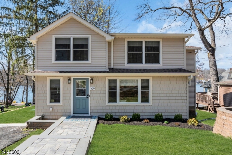 Experience the lake lifestyle without the lakefront price! Beautifully renovated with today's most sought-after designer finishes, this exceptional home feels like a year-round vacation retreat. Just steps from New Jersey's largest recreational lake, enjoy seasonal lake views, optional membership to a private beach club, and protected woodland hiking trails directly across the street. The thoughtfully designed floor plan offers the convenience of a first-floor primary suite featuring a spacious walk-in closet and private full bath. The sun-filled living room flows effortlessly into the dining area and stunning white kitchen appointed with quartz countertops, abundant cabinetry, recessed lighting, and luxury vinyl flooring that continues throughout both levels. Upstairs you'll find three additional bedrooms, a versatile den perfect for a home office or playroom, a beautifully updated full bath, and convenient second-floor laundry. Fresh neutral d cor, quality craftsmanship, and stylish finishes make this home truly move-in ready. Step outside to a deck overlooking the backyard, creating the perfect setting for entertaining, relaxing, or enjoying warm summer evenings after a day on the lake.  Located just minutes from waterfront restaurants, marinas, shopping, golf, hiking and biking trails, and NJ Transit with convenient access to NYC. This turnkey home offers an unbeatable combination of luxury, recreation, and value in one of Lake Hopatcong's most desirable locations.