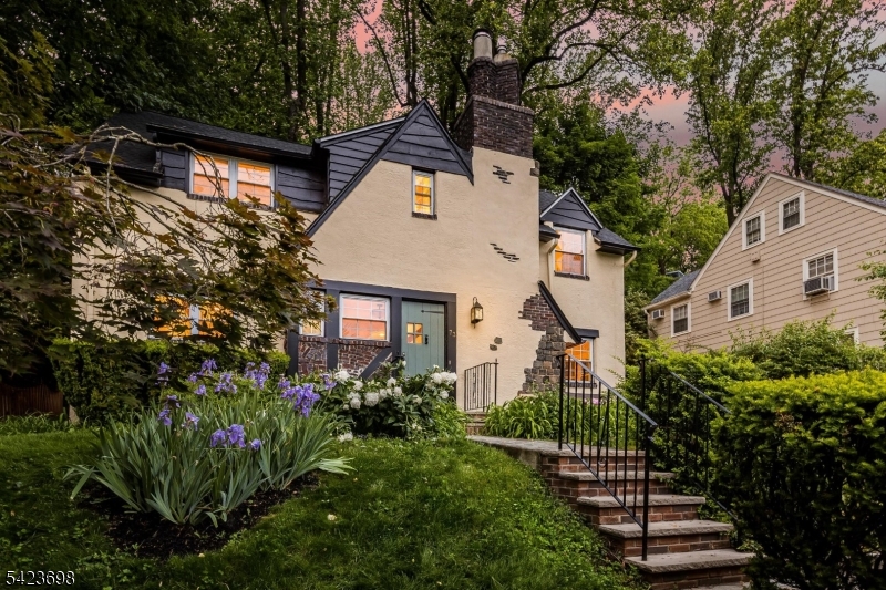 Perfectly marvelous Tudor offering timeless character, thoughtful updates, and stunning NYC skyline views. This 4-bedroom, 3.1-bath home blends classic architectural details with modern comfort, featuring newly refinished hardwood floors, beamed ceilings, charming stucco walls, central air, and abundant natural light throughout. The spacious kitchen/family room combination creates a true "great room  feel ideal for everyday living and entertaining, while the warm dining room easily accommodates both intimate dinners and large gatherings. The inviting living room with distinctive brown Delft tile fireplace wall is perfect for cozy evenings at home. Upstairs, find four spacious bedrooms, full hall bath, and a second Jack & Jill ensuite full bath. Outdoor spaces include beautifully landscaped three-season gardens, sunny front sitting patio, rear patio with gas grill, and peaceful backyard views with no homes directly behind the property, creating a serene, country-like setting. Recent updates include refinished hardwood floors and full interior/exterior painting (2026), new flat roof and skylights over family room/den (2023), central air system (2022), second-floor bath renovation (2021),powder room renovation (2018), rear roof replacement (2015), and bluestone front patio and rear patio improvements (2014). Conveniently located near top-rated schools, South Mountain Reservation, Maplewood Village, Midtown Direct NYC trains, shopping, dining, and parks.