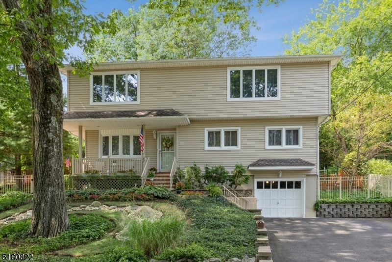 Spacious, private backyard, convenient location! Beautifully kept Colonial offers 4BD, 2BTH, an attached one-car garage, and a fabulous backyard deck. This exceptional home sits on a manicured lot in Bloomingdale, close to schools, shopping, dining, parks, and Routes 287 and 23. Full of charm and character this wonderful mid-century home presents hardwood and tile floors, large rooms with lots of natural light, and great entertaining spaces inside and out. From the welcoming front porch, step inside to a beautiful floating staircase in the foyer defining the open design living and dining areas. The bright, sunny kitchen includes a breakfast nook with a granite topped table for morning coffee or afternoon snacks. Sliding glass doors open to a sprawling multi-level deck that spans the entire width of the house, offering several seating, lounging, and additional storage spaces all overlooking the manicured back lawn "the perfect setting for warm weather entertaining. A bedroom and a full bathroom complete the main level. Upstairs is the lavish primary bedroom complete with a sitting area and sliding glass doors to a cozy balcony looking out on the private back yard. There are two additional large bedrooms and a dazzling tile bathroom updated with a luxurious, jetted corner tub and a bidet.  Even more living space has been created in the finished basement offering a large recreation room, a separate sitting area with a wood-burning stove, a laundry room, and access to the garage.