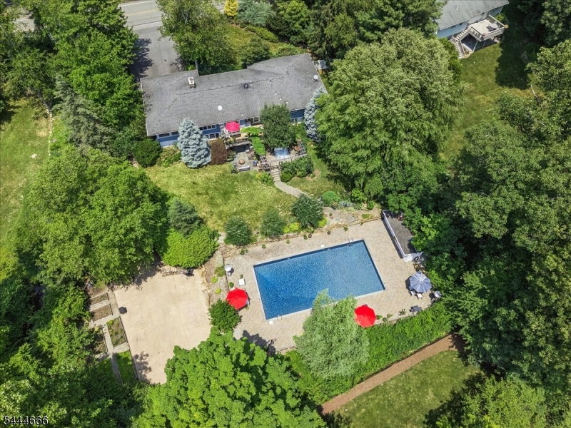 Set on approx. 0.79 acres in Randolph's sought-after Shongum Lake section, this 3-bed, 3-bath Ranch with attached 2-car garage offers the perfect blend of comfort, lifestyle, and resort-style outdoor living. Step inside to a welcoming foyer that opens to a sun-filled living room with hardwood floors, crown molding, raised-panel wainscoting, and a wood-burning fireplace flanked by built-ins. The spacious kitchen features granite counters, ample cabinetry, high-end appliances, a bright breakfast nook, and direct access to the multi-level deck, ideal for morning coffee or evening cocktails. A formal dining room and window-lined sunroom overlook the private, park-like property. The bedroom wing includes a serene primary suite with a spa-like bath featuring a soaking tub, open tile shower, and vanity. Two additional bedrooms share a full hall bath with dual sinks. The finished walkout lower level expands the living space with a recreation room, game area, wet bar, full bath, flex room for an office, gym, or guest space, plus storage. Outside, enjoy a true backyard oasis with a hot tub, heated in-ground pool, expansive paver patio, and wooded privacy. Deeded Shongum Lake rights provide access to the clubhouse, private beach, boating, fishing, swim team, playground, sports courts, and year-round community events. Close to highly regarded schools, dining, shopping, and NYC direct train service. A rare opportunity to enjoy lake living, privacy, and everyday convenience in one setting.