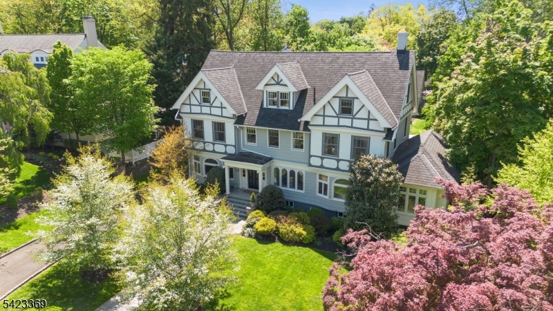 Exquisite Tudor Revival masterpiece situated on a rare .60-acre double lot in South Orange's coveted Montrose Section. Merging Gilded Age grandeur with designer updates, this turn-key estate offers unparalleled luxury. The Chef's Gourmet Kitchen (2022) is a culinary dream featuring quartz surfaces, a 10 ft island, Viking/Bosch appliances, dual dishwashers, gas Fireplace and a massive Butler's Pantry. Entertain in the majestic Living Room with coffered ceilings, the Formal Dining Room or the gut-renovated Family Room (2019) boasting radiant heat floors and Cathedral ceilings.The second level features a sanctuary-like Primary Retreat with an updated ensuite bath and dressing room, plus two additional en-suite bedrooms, offering a modern layout rarely found in historic homes. Finished across four levels, recent 2025/26 improvements include fresh exterior paint in Light French Gray and new designer carpeting. Experience "Hamptons-style" indoor-outdoor living in the heated 3-season screened porch, which flows to a sprawling bluestone patio with a built-in gas fireplace and grill. Smart home integration includes Lutron Caseta lighting, Nest/Google security, EV charger and a whole-house generator. The detached 3-car carriage house with a multi-room loft provides endless potential for a sophisticated home office or ADU (see renderings). Prime commuter location just .4 mi to Mountain Station for NYC train. Historic integrity meets high-efficiency luxury your Montrose lifestyle awaits.