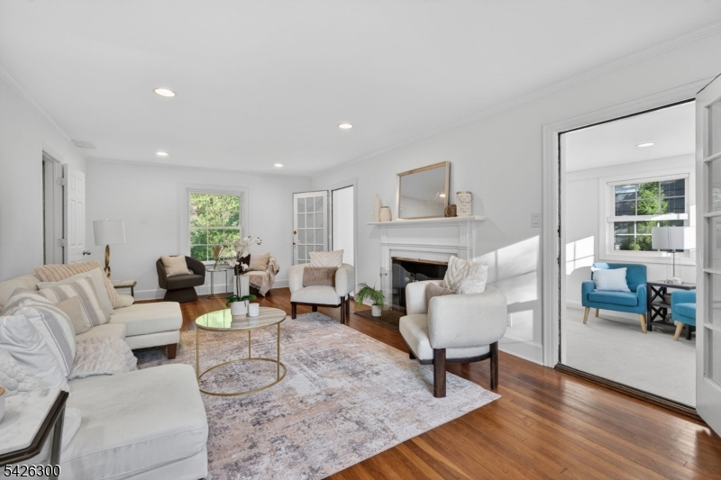 Exceptional Center Hall Colonial nestled in the highly sought-after Knollwood section of Short Hills, just blocks from vibrant downtown Millburn, Midtown Direct trains to New York City, and top-rated Millburn schools. Filled with natural light, the living room features newer windows, a classic wood-burning fireplace and elegant French doors opening to a den or home office. The den offers newly installed carpeting, recessed lighting and walls of windows overlooking the beautiful front and back yards. The formal dining room is rich in timeless charm with chair rail molding and abundant sunlight. The beautifully updated eat-in kitchen showcases white cabinetry, quartz countertops, stainless steel appliances, breakfast island, separate dining area + direct access to the sunroom, private backyard with breezeway 2-car garage. Upstairs, the spacious primary suite features hardwood floors, walk-in cedar closet and a newly renovated bath with sleek finishes and floating vanity. Additional bedrooms are bright and generously sized with hardwood floors and ample closet space, while the updated hall bath is finished in travertine marble. The 3rd floor adds two flexible rooms perfect for bedrooms, offices, or guest space. The freshly painted lower level provides new carpeting, exceptional storage, utility space + walkout access. With extensive updates + unbeatable location near shopping, dining, transportation and Newark Airport, 85 Whitney Rd offers the best of refined suburban living