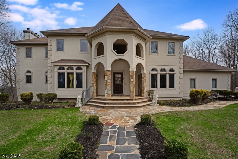 Sparta: Exquisite Colonial nestled at the end of a cul-de-sac with stunning mountain views in a charming neighborhood, close to commuter routes. Step inside through the elegant stone & stucco turret into a bright foyer featuring a first-floor home office overlooking the front lawn and water fountain. A half bathroom and laundry/mudroom with access from the 3-car garage are conveniently located to the right. Straight ahead, enjoy the sunken conservatory; to the left, the formal dining room the open living area with a cozy fireplace. The well-equipped kitchen opens to a deck perfect for outdoor dining and overlooks the grand backyard with an in-ground, heated safe pool. Upstairs, the second-floor primary bedroom offers a fireplace and two walk-in closets, along with a spacious primary bath featuring a jetted tub, stall shower, linen storage, and a dedicated water closet. Three additional bedrooms, a second office, and the main bath complete this level. Walkout basement adds even more value with a movie theater, bedroom, kitchenette, full bathroom, and a comfortable play/sitting area. There's also a versatile under-front-porch turret room ideal for a workout space or wine cellar. Enjoy year-round comfort with a geothermal system and dual (2 unit) heat and A/C, helping offset operating costs. A great home to begin your adventures in Sparta, Sussex County minutes to golf courses, hiking trails, skiing, water park, camping, & hunting, plus Tri-State area fine dining restaurants.
