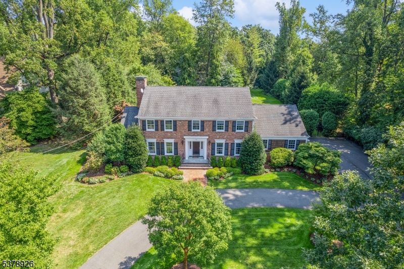 This classic brick Colonial is nestled on an acre of meticulously landscaped property in Essex Fells on over 1 acre, showcasing a masterful blend of traditional warmth and modern convenience. encompassing 6 bedrooms and 4 full and 2 half baths, gracious floor plan, primary bedroom has attached office, 75 foot heated gunite pool, 2 swimming lanes, outdoor shower, circular drive, 3 car heated garage, beautiful sunsets looking west, complete privacy in the back yard, deer free 6' fence in backyard,natural gas grill, whole house natural gas generator, large bluestone patio, hardwood floors, show-stopping gourmet kitchen by Wood Mode, 2 sinks in kitchen each with garbage disposal, Wolf and Sub-Zero appliances, Double Wolf convection ovens, custom tile backsplash, 11' island in kitchen, instant hot and instant cold water, 2 refrigerator drawers, warming drawer, 2 dishwashers, 2 fireplaces, foyer with double closets, built-in wet bar with wine fridge, oversized walk-in closet in primary, oversized jacuzzi, water closet, game room, workout room, bedroom with full bath in lower level, wine cellar