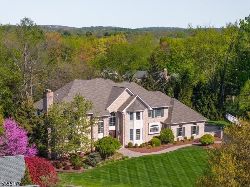 Set on nearly an acre on a cul-de-sac close to town, this beautifully appointed 5 bedroom, 5.1 bath, brick front colonial with 3-car garage and Tesla EV charger, has a finished walkout basement, and recently refinished hardwood flooring. The open first floor plan sets a perfect stage for entertaining with a soaring double height foyer, family room with floor-to-ceiling stone fireplace and a sunlit conservatory. The bright and airy kitchen showcases Taj Mahal quartzite countertops, center island and stainless steel appliances. In addition to an office/living room with gas fireplace and formal dining room, a convenient first-floor bedroom with adjacent full bath and a powder room complete this level. Bringing the outdoors in, the breakfast room opens to the screened porch with knotty pine beadboard vaulted ceiling and expansive deck, both of which provide beautiful views of the large, private yard. Upstairs, the spacious primary suite features a large and light-filled ensuite bath with soaking tub, double vanities, a large shower and three walk-in closets. Three additional bedrooms and two additional baths,  including an ensuite, complete this level. The finished, walk-out basement offers a spacious recreation room, game area, exercise room and a full bath. All this, plus top-rated schools, easy access to transportation, shopping, and dining. This home epitomizes the best of 21st century luxury living.