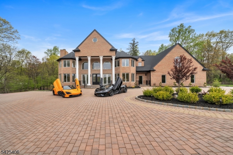 This exceptional custom-built estate blends timeless architecture with a refined contemporary aesthetic, offering resort-style living on a private cul-de-sac. Surrounded by natural beauty and mountain views, this recently renovated residence spans approximately 11,850 square feet across 4 impeccably finished levels. A grand paver driveway leads to an impressive facade and a dramatic two-story foyer, showcasing a sweeping butterfly staircase. The sun-filled family room is a true focal point, featuring a mezzanine overlook, gas fireplace, lots of windows that bring in natural light while framing the serene, landscaped grounds. The gourmet kitchen is designed for both everyday living and effortless entertaining, complete with oversized center island, sink with dual faucets, 2 dishwashers, spacious walk-in pantry. Seamlessly connecting indoor and outdoor living, the kitchen and family room open to a private backyard retreat featuring a bluestone patio and a heated in-ground pool with a waterfall perfect for entertaining or relaxing in a tranquil setting. The third floor is dedicated to entertainment, featuring a stunning home theater. The walk-out lower level is designed for hosting on any scale, offering a full bar, dance floor, lounge area, and a second kitchen, creating the ultimate entertainment space. Additional highlights include a 3-car garage with capacity for up to 5 vehicles. Close proximity to major highways and NYC access.