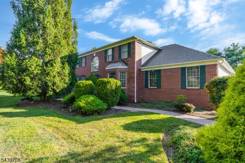 First time ever offered. The same original owners have cared for this brick front Colonial in Greenwood Meadows since it was built in 1994, and the big ticket items are already handled with a newer roof, newer HVAC, and newer paved driveway, all replaced in recent years. That frees you to focus your budget where it counts, updating the largely original interior to your own taste. Approximately 3,698 sq ft begins at a two story foyer with a curved staircase. Hardwood floors and crown molding carry through the bay windowed formal living room and the formal dining room with chair rail, while oversized windows fill the home with natural light. The sunken family room with its brick fireplace opens to the eat in kitchen with oak cabinetry and a breakfast bar, all overlooking the deck and level backyard. A three car side entry garage adds everyday convenience. Set on .73 professionally landscaped acres with a paver walkway and mature plantings, the lot is level and open with a private feel at the rear. Located in the Watchung Hills Regional High School district, minutes to Pingry, Warren schools, parks, shopping, and major commuter routes. Well kept, one owner homes rarely reach the market here. Bring your vision and make this Greenwood Meadows classic your own.