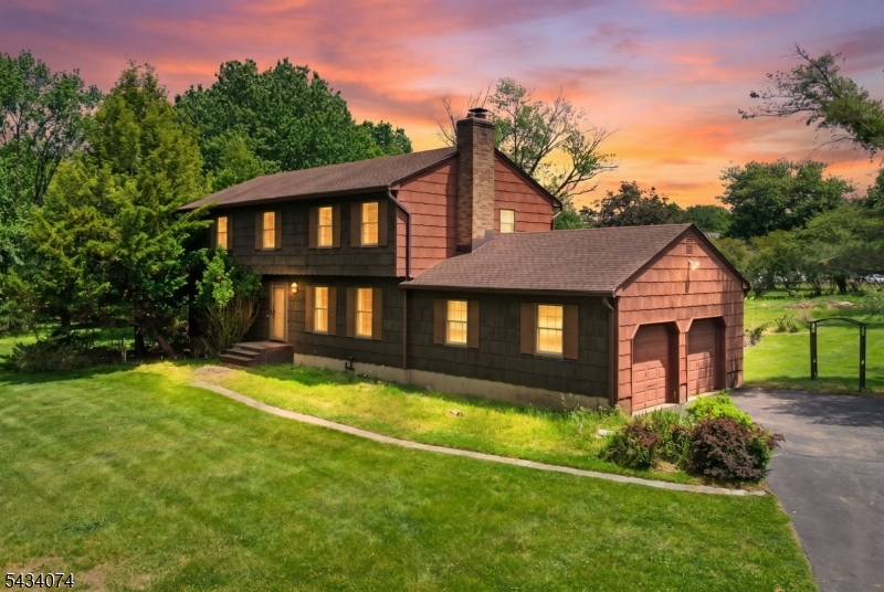 Welcome to this spacious and beautifully maintained 4 bedroom, 2.5 bath colonial set on approximately 1.8 acres in desirable Neshanic Station. Located at 42 Higginsville Road, this home offers a peaceful setting with plenty of room both inside and out. Featuring a classic wood siding exterior, mature landscaping, and a large driveway leading to a 2 car garage, the property blends charm, privacy, and functionality. Inside, the first floor offers a traditional yet open layout with a large living room, formal dining room, and an oversized family room with wood burning fireplace and sliding doors leading to the backyard. The eat in kitchen provides abundant cabinet space and overlooks the private yard, making it ideal for everyday living and entertaining. Upstairs, hardwood flooring runs throughout all four generously sized bedrooms. The spacious primary suite includes its own full bath, while an additional full guest bath serves the remaining bedrooms. A huge walk up attic offers tremendous storage potential or future finishing possibilities. Additional features include a large dry basement, septic system, private well, above ground oil heat, central air conditioning, and a roof estimated to be approximately 10 to 15 years old. Set on a beautiful lot in a highly sought after section of Readington Township with top rated schools and convenient access to shopping, dining, and major commuting routes, this property offers endless potential to make it your own.