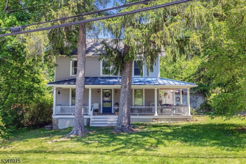 Comfortable historic 1920 colonial in the quaint town of Califon, nestled in Hunterdon County. Covered wrap-around front porch has a view of mature pine trees, creating a natural fence in the front yard and the rear yard features a brick patio overlooking perennial gardens and small fish pond. 1st floor features 5 year old porch, spacious dining room with decorative fireplace, light and bright kitchen, living room with woodburning stove. Second floor offers primary suite with wood floors and skylight, 3 additional bedrooms and updated main bath with tub shower and new vanity. Walk-up attic adds additional storage and possibilities for living space. Great elementary schools and Vorhees High School. **NEW 4 Bedroom septic system being installed**