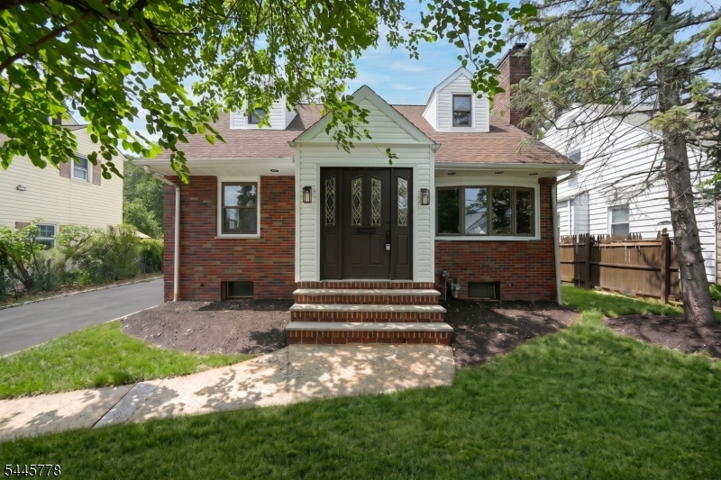 This beautifully updated Cape Cod is the epitome of modern renovation, and it shows the moment you arrive. A paved driveway leads to a brick-accented facade, manicured landscaping, and a stained glass front door that sets the tone for the quality found throughout. Inside, the living room features rich hardwood floors, a stone fireplace, and recessed lighting that flows seamlessly into the formal dining room anchored by a striking chandelier. The updated eat-in kitchen is a standout boasting two-tone cabinetry with warm wood uppers and crisp lowers, and spacious countertops. The adjacent family room offers an oversized picture window, and direct access to the backyard. Two first-floor bedrooms and a full bathroom with updated vanity complete the main level. Upstairs, the primary suite delivers generous proportions, a sitting alcove, and a stunning en-suite with glass shower enclosure. A second bedroom rounds out the upper level. The finished basement expands your living space with a family room, half bathroom, and laundry. Outside, a sprawling backyard with mature trees and lush hedges awaits. Just half a mile from bus transportation at Vauxhall Road and minutes from I-78.