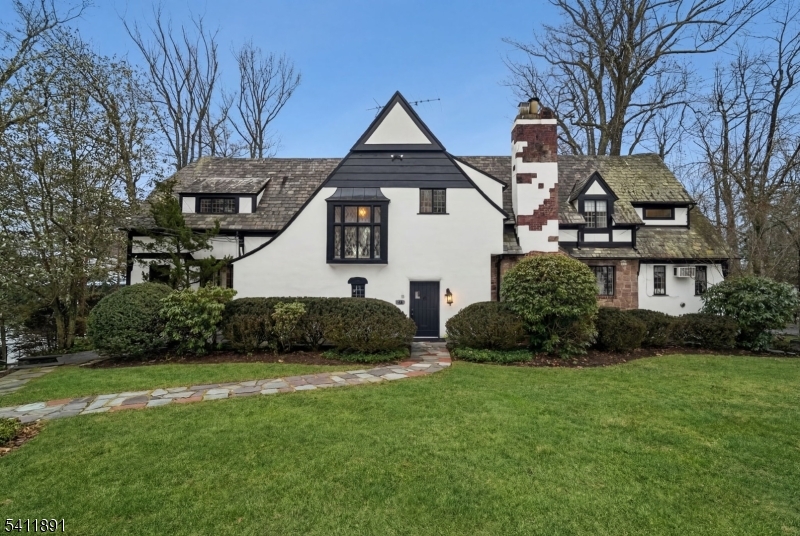 Mint condition incredibly bright Tudor renovated to perfection, ideally located on .34 acres on coveted quiet street walking distance to Millburn & Short Hills Train Stations, downtown Millburn & Millburn Middle School, and close to highly rated Hartshorn Elementary School. Stunning new gourmet eat-in kitchen is a chef's dream with huge center island, custom cabinetry, pantry, top of the line Gaggenau, Dacor, Viking & Miele appliances with tin ceiling & radiant heated tile floor. Tremendous natural light from new windows & doors & eating area with great views & easy access via new French doors to terrace with custom wrought iron spiral staircase to flagstone patio & totally level property, surrounded by mature hedges for great privacy. Huge living room with wood-burning fireplace, built-in bookcase & tremendous natural light. Sunroom has great natural light from 3 exposures. Incredible dining room with chandelier, new mudroom with custom cabinetry to side entrance, & powder room. Luxurious Primary Suite with 2 new walk-in closets & spa-like new bath with radiant heated floors. 4 more spacious bedrooms share new bath with radiant heated floors & shower over tub. Convenient 2nd floor laundry. Beautifully finished lower level with walkout recreation room with fireplace and windows providing great natural light, powder room with potential to add shower to be a guest suite. Access to attached heated 2-car garage. Low taxes! This gem in an ideal Short Hills location is a must see!