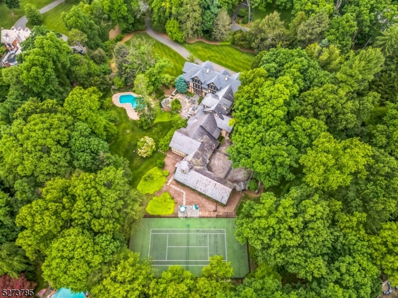 Impressive Tudor manor home is nestled on 3.5 flat acres of arguably the best piece of real estate in Essex County. The spectacular property includes 7 bedrooms,7 full bathrooms, 3 half bathrooms, a swimming pool, a tennis/pickleball court, and garages for 4 cars. With its highly regarded schools, grand homes, and close-knit community, this soulght-after location offers the epitome of luxury living.A sweeping front lawn and cobblestone courtyard bring you to the inviting entrance. Step inside to a magnificent interior perfect for entertaining with rich hardwood floors, elegant molding and trimwork, plaster ceiling flower designs,abundant natural light, and every modern amenity one could want. Beautifully scaled rooms and gorgeous views define this extraordinary home featuring exceptoinal craftsmanship and archetectural details throughout. Main level includes banquet-sized formal dining room,home movie theater,living room with floor to ceiling bow windows,library,huge gourmet kitchen, Second floor primary suite with sitting room and large walk-in closet, 2 additional bedrooms each with own en suite bathroom, walk-in closet and sitting room, Two offices a full hall bathroom and a kitchenette/wet bar.The third floor has 3 large bedrooms, multiple walk-in closets,3 full baths, large bonus room,and easy attic storage access. The lower level features a home gym,powder room, and plentiful storage. Sprawling patio,stone gazebo,tennis court, and swimming pool and gas generator.