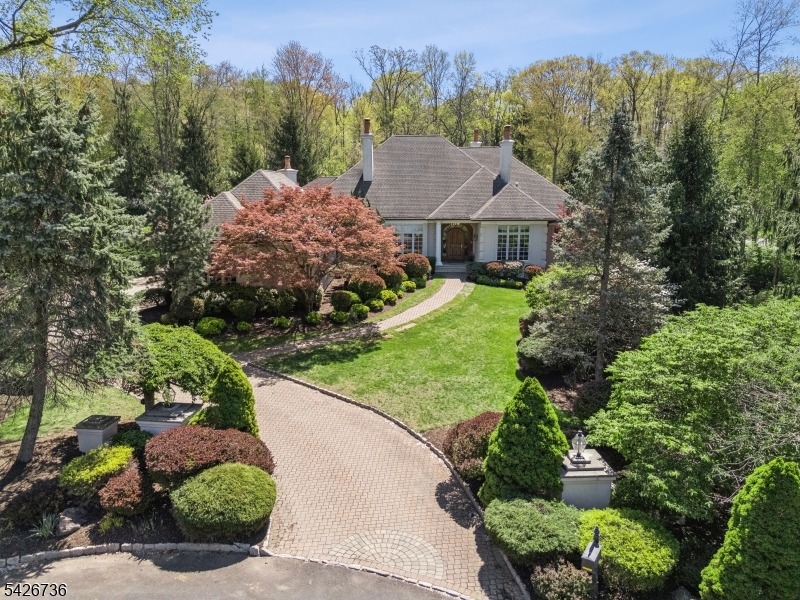 Custom architecture meets an unforgettable setting in this stunning ranch-style retreat with a first-floor primary suite.  Ideally positioned at the end of a quiet cul-de-sac in Watchung's most prestigious neighborhood. Designed to embrace its surroundings, this home was thoughtfully built to wrap around a private backyard oasis offering two distinct outdoor living spaces, a heated saltwater pool, and a tiered landscape that creates breathtaking views from nearly every room. The seamless connection between indoor & outdoor living is simply exceptional. The gourmet eat-in kitchen features top-of-the-line appliances, a large center island, & generous space for gathering. Just beyond, the great room is filled with natural light, with walls of windows that bring the outdoors in. A sophisticated office with floor-to-ceiling custom built-ins, a coffered ceiling, & a gas fireplace offers the perfect work-from-home sanctuary. The first-floor primary suite is a true retreat, complete with a tray ceiling, spa-like ensuite bath, two oversized walk-in closets, & direct access to the deck. A second first-floor ensuite provides flexibility for guests, while three additional bedrooms upstairs offer ample space. The expansive lower level features high ceilings and is plumbed for a future bathroom. Located just moments from the Watchung Lake, Route 78, The Pingry School, & ten mins from various train stations, a perfect combination of luxury & convenience.
