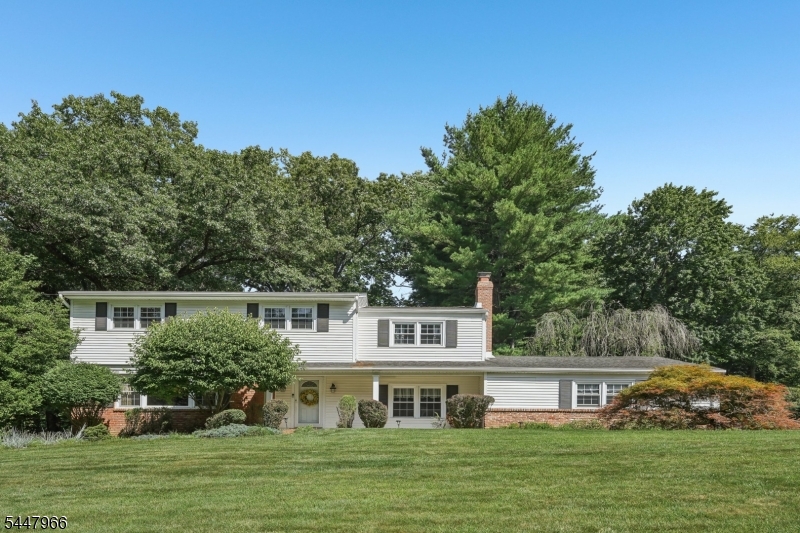 Welcome home to this beautifully maintained 5 bedroom 3.5 bathroom Colonial nestled on a manicured lot with nearly an acre of private property, offering privacy and outdoor enjoyment. A paver walkway leads to the covered front porch, creating a warm welcome. Step inside the foyer and into the sunlit living room, where a large picture window fills the space with natural light. A wide cased opening flows into the elegant dining room, perfect for everyday meals or entertaining. The well-appointed kitchen features custom cabinetry, granite countertops, stylish backsplash, stainless steel appliances, and breakfast nook. Sliding glass doors open to the rear patio, creating indoor-outdoor living. The spacious family room with wood-burning fireplace provides the perfect setting for relaxing or gathering. A first-floor bedroom, laundry room, and powder room add everyday convenience. Upstairs, the primary suite features a walk-in closet and private en suite, while three additional bedrooms and full bathroom complete the level. The finished basement offers a versatile den ideal for movie nights, games, or recreation. Outside, enjoy your own backyard retreat with a sprawling paver patio, gunite in-ground pool, and pool house complete with outdoor kitchen, bathroom, and storage, creating the ultimate space for entertaining all summer long. A 2-car attached garage and ample driveway parking complete this exceptional home, conveniently located near NYC transportation, shopping, and dining.