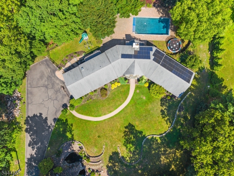 Nestled on the edge of High Mountain Park Preserve, this exceptional 4-acre private estate offers unmatched seclusion, breathtaking natural surroundings, and direct access to hiking trails right from your backyard.Step inside to a bright, welcoming foyer that opens to a spacious family room featuring a gas fireplace and elegant French doors. The formal dining room is ideal for entertaining, while the oversized custom eat-in kitchen is a chef's dream, complete with granite countertops, two dishwashers, stacked wall ovens, a six-burner cooktop, and abundant cabinetry.The home offers five generously sized bedrooms, including a luxurious primary suite with a walk-in closet and a spa-inspired bathroom featuring heated floors. A Jack-and-Jill bathroom with a private toilet and shower area, along with an additional full hall bath, provides comfort and convenience for family and guests.Beautifully updated in 2023, this home offers approximately 3,000 square feet of additional living space in the expansive walkout lower level. Designed for both entertaining and extended living, it features a custom-made second eat-in kitchen, second laundry room, wet bar, steam shower, alder wood sauna, and fitness room.Outside, enjoy your own resort-style home with patio and bar, in-ground pool, tranquil fish pond, private playground, outdoor stone fireplace, built-in BBQ, relaxing in complete privacy.Additional highlights include hardwood floors throughout and fully paid-off solar panels.
