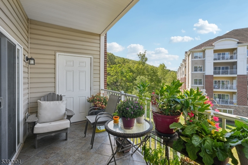 Welcome to this beautiful Colfax END-UNIT condo in one of the newer buildings of Wanaque Reserve, an active adult 55+ community. Move-in ready and filled with natural light, this 2-bedroom, 2-bath home offers picturesque views of the mountains and pond. The open floor plan features unique polished concrete floors, a spacious den with French doors that open to the dining room, and sliding glass doors that lead to a tiled balcony perfect for relaxing. The primary bedroom suite is a true retreat with a tray ceiling, walk-in closet, additional double closet, dressing area, and a private ensuite bath. A second bedroom, full bath, and in-unit laundry provide comfort and convenience. This home also includes TWO DEEDED UNDERGROUND PARKING SPACES. New hot water heater with auto shut off valve. Wanaque Reserve offers a resort-style lifestyle with a clubhouse that features a cafe , fitness center, theater, sauna, ballroom, and both indoor and outdoor pools. With more than 45 clubs and activities, including travel, tennis, pickleball, golf, canasta, and poker, there is something for everyone. This property combines comfort, style, and community in one of the area's most sought-after locations. HOA fee also includes cable and internet