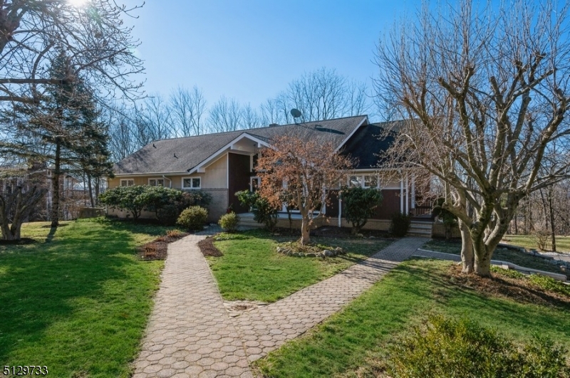 Spacious, sweeping views, prime location! Expanded Ranch with 6B, 4 1/2 BTH. Showcasing spectacular treetop views of the countryside, this home features lots of natural light, a deck spanning the full length of the home and a large patio on just over an acre of park-like property. The vast landscaped backyard features a wood burning fire pit and a natural trail like exercise-walking path. From the front porch, enter the foyer with a dramatic 2 story ceiling flowing to a spacious open LR & DR with gleaming hardwood floors. 3 sets of sliding glass doors fill this space with light and panoramic views. The LR has a warming fireplace with a floor-to-ceiling brick surround and directly flowing into the adjacent formal DR.  The eat-in kitchen equipped with plenty of counter space and stainless steel appliances and bright breakfast area. The layout continues to an office a full BTH, 2 bedrooms and the primary bedroom suite with a private bath.  The second floor encompasses 3 additional bedrooms, 2 full BTH and 2 generous storage spaces. The walk-out finished basement level offers a huge FR perfect for entertaining with 2 sets of sliding glass doors opening to the stone paver patio and sprawling back yard lawn with beautiful views beyond the trees. This level also has 1/2 BTH, ample storage and access to the oversized 2-car garage. Set in a community blending rural charm and urban convenience, this home is close to schools, shops, restaurants, parks, and convenient commuting options.