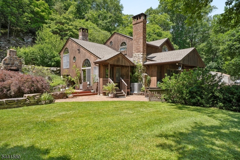 This beautifully updated, light-filled home offers a sophisticated contemporary flair with thoughtful upgrades throughout. Featuring 3 bedrooms and 3 baths, the residence blends style, comfort, and functionality.  A large, inviting living room with fireplace provides the perfect gathering space with a high ceiling and skylights flooding the room with light.  A stunning modern kitchen complete with a cozy fireplace, center island, rich cherry cabinetry, stainless steel appliances, new granite countertops and backsplash and a custom built-in bar ideal for everyday living and entertaining. Gleaming hardwood floors flow throughout.  The primary suite is a true retreat, featuring a vaulted ceiling, walk-in closets, and a newly renovated spa-like bathroom designed for relaxation. The home is complemented by abundant storage, full walk-out basement for convenience.  Additional highlights include a newer HVAC system and roof.  Step outside to your own private backyard nature oasis, showcasing a spacious deck, side yard, stone patio with firepit, fruit trees, a tranquil koi pond, and waterfall perfect for outdoor entertaining or peaceful unwinding. Conveniently located close to major highways, public transportation, restaurants, and shopping, this exceptional home offers the perfect balance of privacy, style, and accessibility.