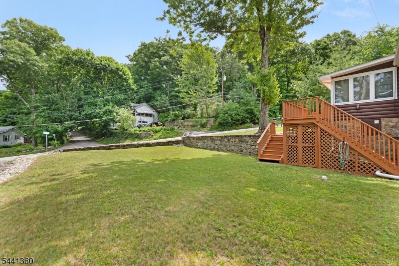 Welcome to 41 E Shore Road, a charming Lake Hopatcong-area cottage with a warm cabin feel, inviting indoor/outdoor living, and thoughtful updates throughout. Technically a 2-bedroom home with a 2-bedroom septic, the current floor plan is configured as a spacious 1-bedroom layout with a large walk-in closet, offering flexibility for future use. The bright main living area features exposed wood beams, generous windows, and an open dining/sunroom space overlooking the deck and yard. The kitchen offers newer appliances including oven, microwave, and dishwasher, while the bath was renovated in 2021. Major improvements include a new roof and electric water heater in 2017, high-efficiency furnace in 2018/2019, new electric panel with portable generator plug-in in 2023, natural gas line in 2025, and freshly painted deck in 2026. Outside, enjoy a fenced-feel setting with lawn space, stone walls, off-street parking, storage shed, and an updated patio with lighting tucked into a private natural backdrop. Close to lake recreation, East Shore Park, shopping, dining, and commuter routes.