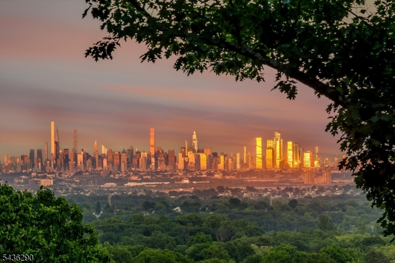 Perched on prestigious Highland Avenue, this architecturally striking mid-century modern offers breathtaking panoramic view of the Manhattan skyline and an exceptional blend of design, comfort, and lifestyle. Renovated in 2022 and 2025, the home is flooded with natural light and boasts an open-concept floor plan, soaring ceilings, radiant heated wood floors, and walls of glass that seamlessly connect the interior to the surrounding landscape. A gracious foyer with dramatic staircase and oversized picture window sets the tone, while the spectacular living, dining and kitchen spaces are designed for both everyday living and effortless entertaining. The gourmet kitchen features a large quartz center island, premium stainless appliances, wine refrigerator, coffee bar with open shelving and direct access to an expansive balcony  with outdoor speakers and powerful heaters, allowing year-round enjoyment of the iconic skyline views. The home offers four bedrooms, three beautifully updated bathrooms, custom closets throughout, electric shades in the main bedrooms, and a cedar hall closet. The versatile ground level includes a bedroom, recreation/lounge/office area, full bath, laundry and storage. Additional highlights include a whole house generator, Vivint security system, newly fenced backyard with patio, attached two-car garage with epoxy flooring, new refrigerator and new washer and dryer. Ideally located just moments from Upper Montclair village, NYC direct train, parks.